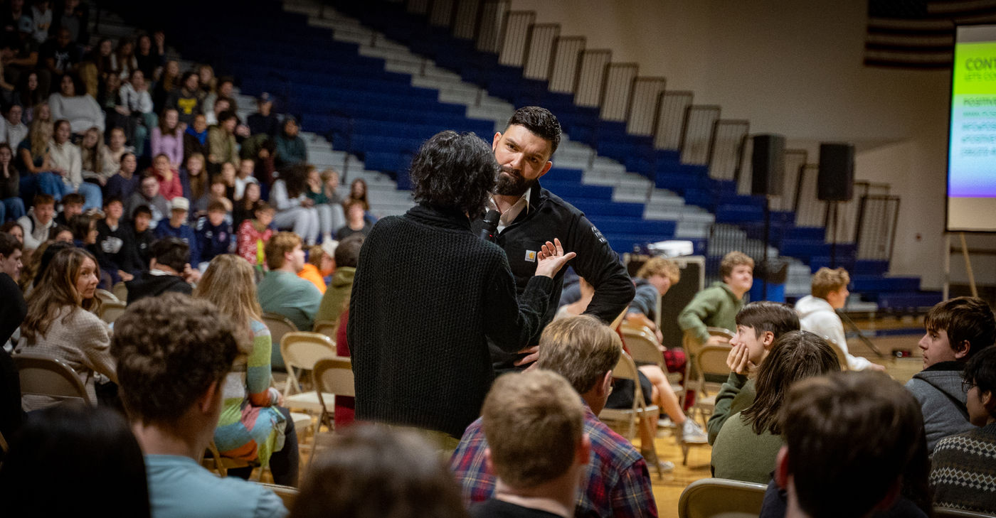 A Youniversal Learning speaker connecting with a student during a packed school assembly